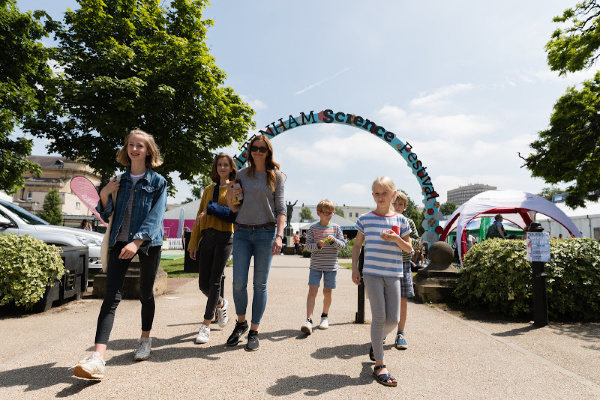 Cheltenham Science Festival entrance arch with people walking towards the camera